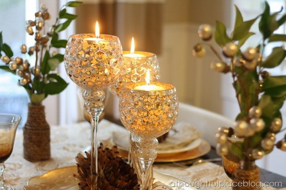 "Close-up of a festive Gold and Green Holiday Tablescape featuring a trio of Decorative Crystal Candlesticks with lit white candles. The elegant display, set on a dining table, provides a beautiful, Inviting Dinner Party Ambiance for guests."