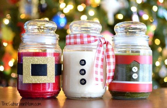 "Trio of Novelty DIY Holiday Jars decorated as Christmas character outfits: Red Santa belt, white snowman buttons, and green elf belt. These festive containers feature a warm background glow, perfect for Handmade Christmas Decor or Fun Christmas Centerpieces."