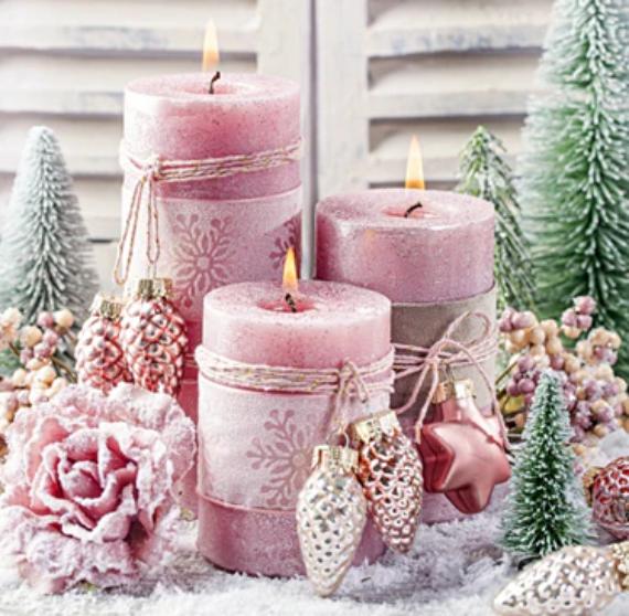 Elegant decorative Christmas candles in soft pink tones surrounded by fir trees, snowflakes, and ornaments, creating a cozy pastel winter holiday ambiance.