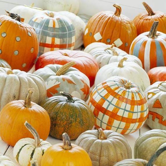 An assorted collection of pumpkins and gourds in various sizes, colors, and patterns, including painted plaids and polka dots, is arranged closely together for a festive autumn display.