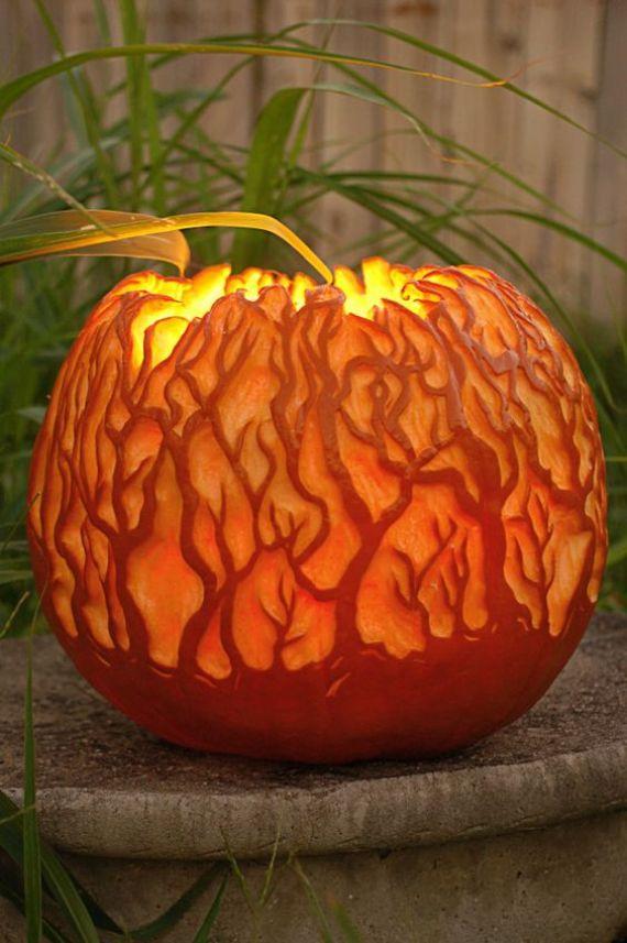 Creative Pumpkin Carving with intricate tree designs glows warmly in a dim setting, evoking a mysterious, enchanting autumn atmosphere.