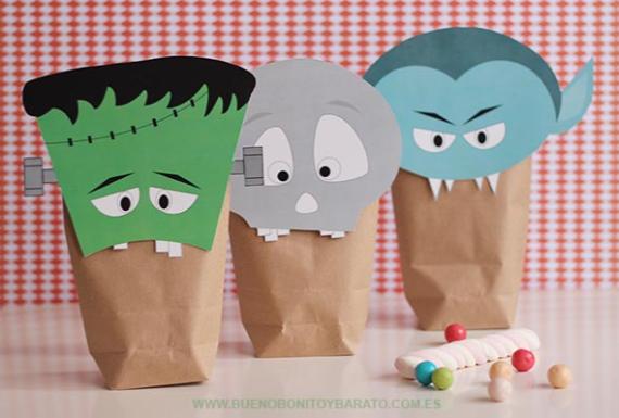 Three Easy DIY Halloween Bags for Kidsdecorated as monster faces with colorful paper: a green Frankenstein, a gray skull, and a blue vampire. Background is a red checkered pattern.