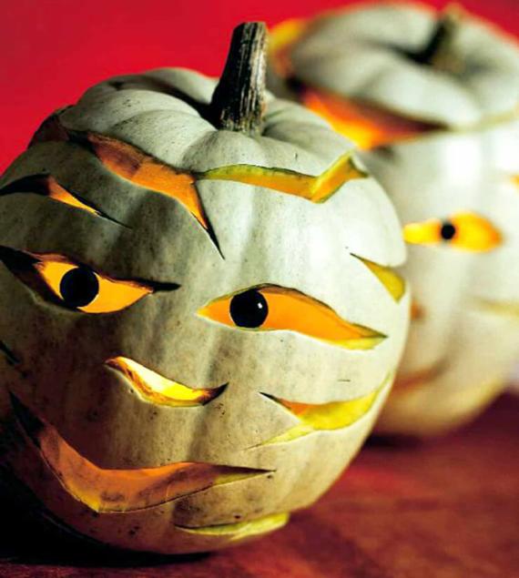 Two Pumpkin Jack-O’-Lantern Carving Idea carved on white pumpkins with glowing orange eyes and mouths, set against a red background. Their expressions are mischievous and playful.
