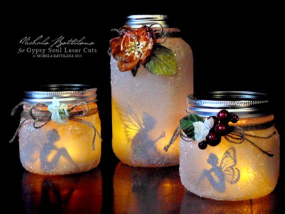 Three frosted mason jars with lids glow warmly, each decorated with flowers and berries. Inside, fairy silhouettes create a whimsical, magical ambiance.