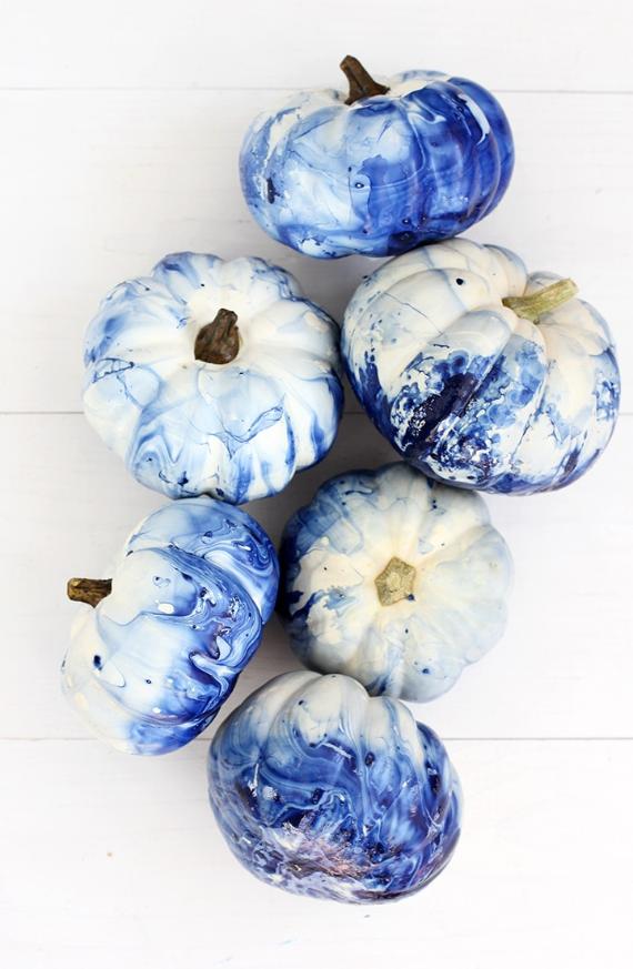 Six pumpkins with a marbled blue and white pattern are arranged on a white background. The colors blend artistically, creating a serene effect.