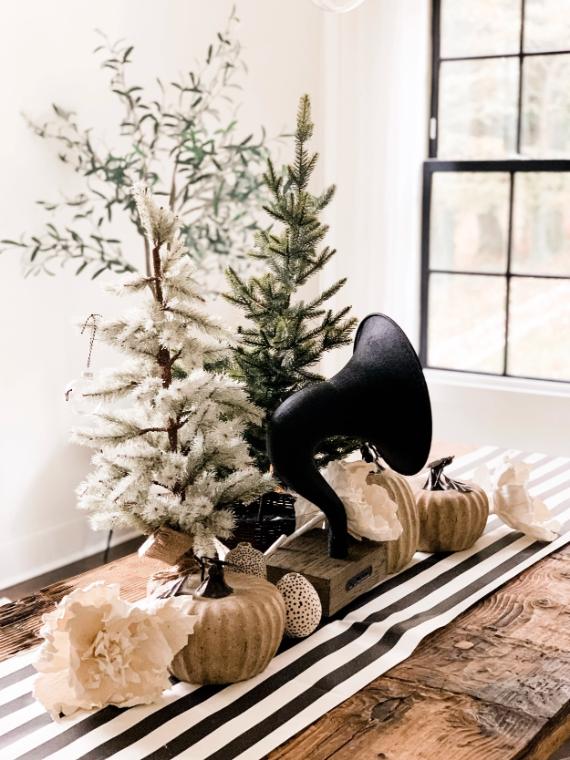 Decorative arrangement with artificial trees, pumpkins, and a phonograph horn on a rustic table.
