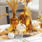 a-beautiful-rust-and-gold-centerpiece-of-pumpkins-apothecary-bottles-with-grasses-and-leaves-and-lights