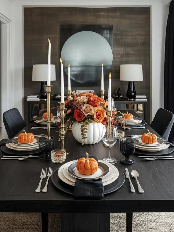 A dining table with a fall-themed centerpiece of flowers in a pumpkin vase, surrounded by candles, pumpkins, and elegant tableware.