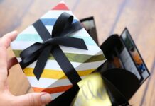 30 Unusual and Unique Mother Day Homemade Gift Ideas A hand holds a colorful, exploding-box tied with a black ribbon. In the background, an open black box reveals peek of a yellow paper with "hello."