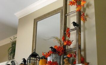 25 Awesome DIY Halloween Decorations A decorative mantle with a ladder, a mirror, and a bird resting on it.