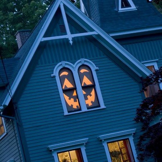 A house featuring a carved pumpkin face displayed in the window, creating a festive Halloween atmosphere.