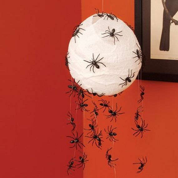 A white paper ball adorned with black spiders hanging from its surface, creating a spooky decoration.
