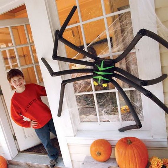 A young boy next to a large spider on a porch, looking intrigued by the creature.