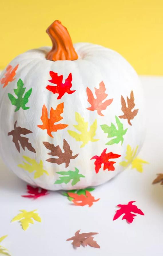 A pumpkin adorned with vibrant, colorful leaves, showcasing a festive autumn decoration.