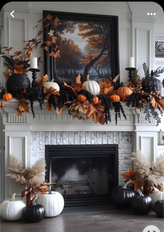  A white fireplace decorated for Halloween with a thick garland of copper leaves, black berries, white and orange pumpkins, black candleholders, and a framed moody forest painting.