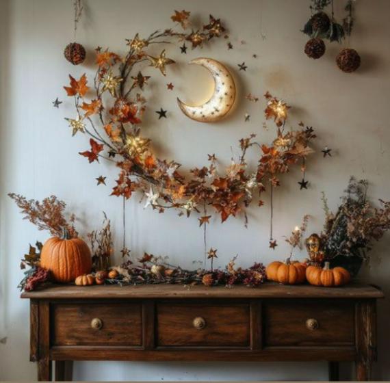  A rustic wooden console table decorated for Halloween with a wall installation featuring a glowing crescent moon, a matching vine-like crescent garland with autumn leaves, glowing star lights, and fresh orange pumpkins.