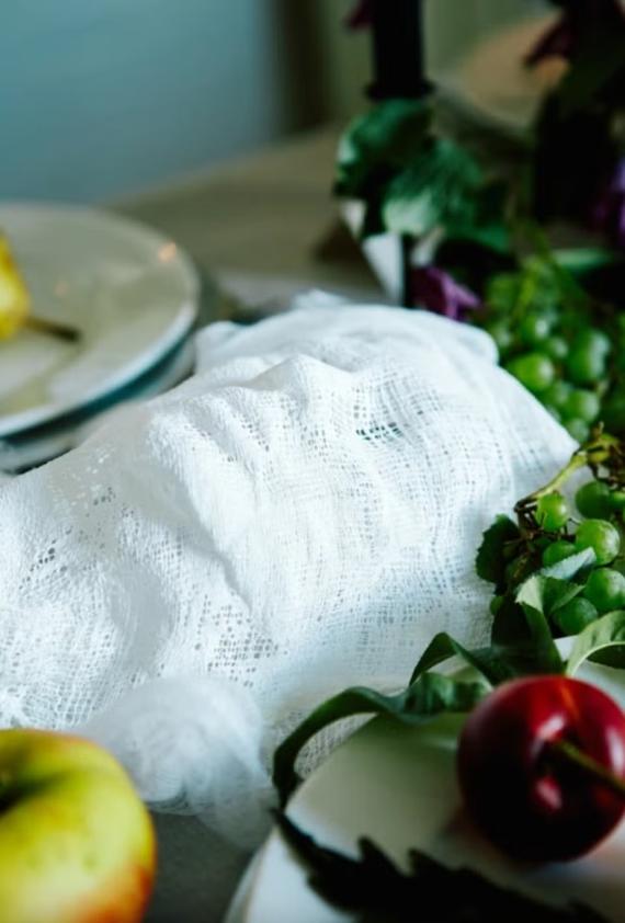 A white cloth covers a table adorned with an assortment of fresh fruits and vegetables.
