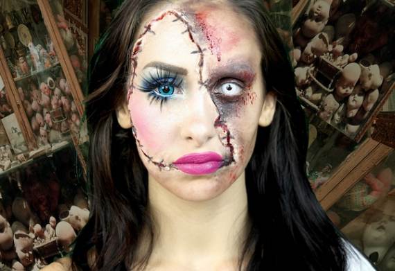 Scary makeup ideas for Halloween of a woman with half-doll, half-zombie makeup stares ahead. Her right eye is blue, the left white. The background is filled with doll parts, creating a creepy atmosphere.