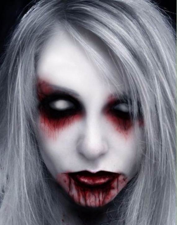 This scary Halloween makeup idea of a Ghostly figure with pale skin, dark sunken eyes, and blood-red lips, conveying a haunting and eerie atmosphere. Hair is light and disheveled.