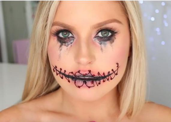Blonde woman with stitched Halloween makeup, featuring smudged black eyeshadow and eyeliner tears, creating an eerie and dramatic look.