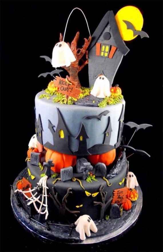 A multi-tiered Halloween cake featuring a friendly haunted house, graveyard tombstones, small ghosts, and pumpkins.