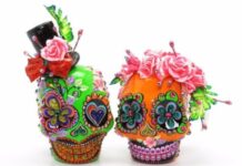 Day of the Dead Mexican Crafts and Activities Two vibrantly colored Day of the Dead sugar skulls—one lime green with a top hat and one bright orange with a pink rose crown—richly decorated with glitter and rhinestones.