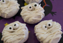 Easy Halloween Treats: Doughnuts of Doom Powdered mini doughnuts decorated as Halloween mummies with white frosting drizzled as bandages and candy eyes on a purple festive plate.