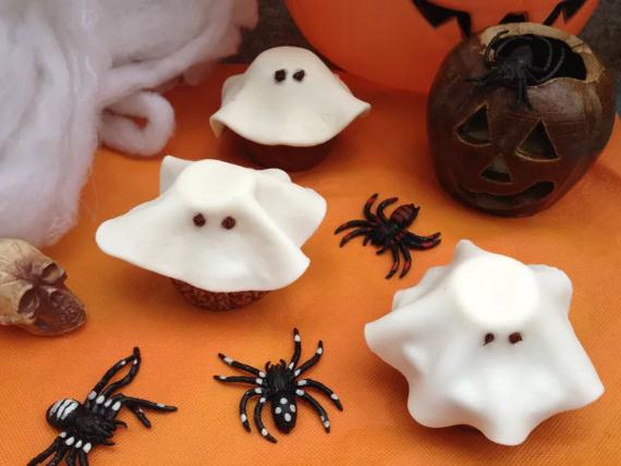 Halloween-themed cupcakes decorated with ghost and spider designs, showcasing festive treats for the holiday.