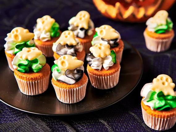 Halloween-themed cupcakes decorated with cute ghost and pumpkin designs, set against a festive backdrop.