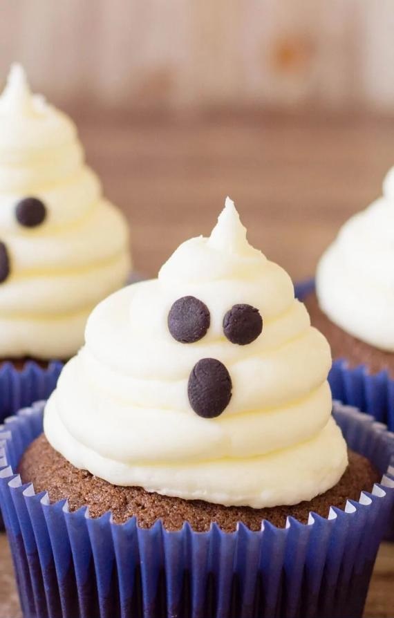 Halloween-themed cupcakes topped with colorful frosting and candy eyes, arranged on a festive display.