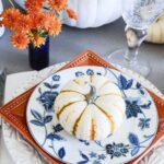 a-stack-of-white-orange-and-blue-and-white-plates-and-a-blue-vase-with-orange-blooms-for-a-chic-Thanksgiving-table