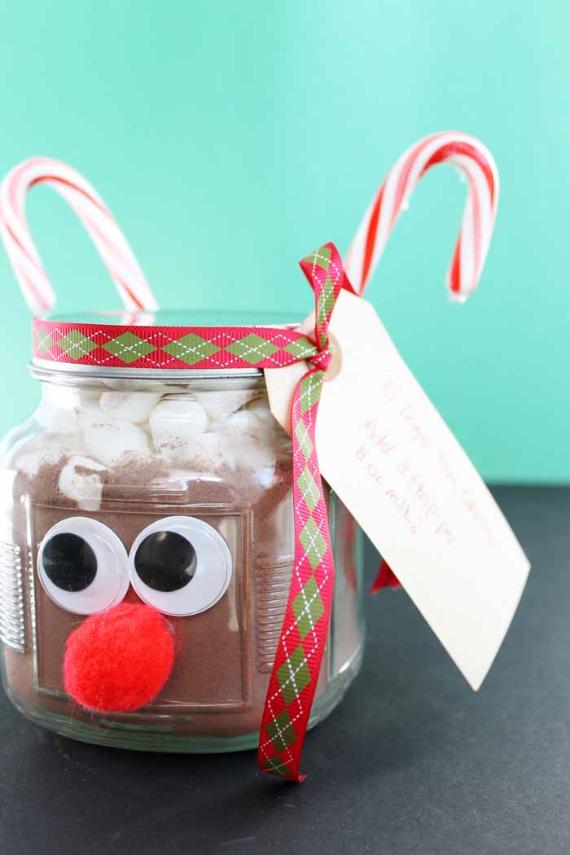 A festive jar filled with hot cocoa mix, decorated as a reindeer with googly eyes, a red pom-pom nose, candy cane antlers, and a plaid ribbon.