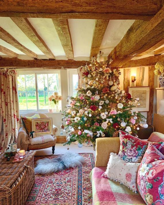 Feminine rustic Christmas decor featuring rose gold tree ornaments, timber beam ceiling, and cozy farmhouse holiday styling