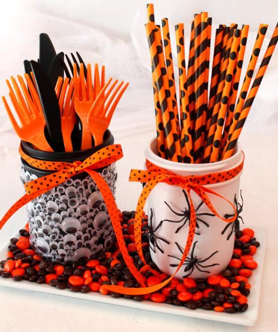 Two jars filled with black and orange candy, accompanied by black and orange forks placed beside them.