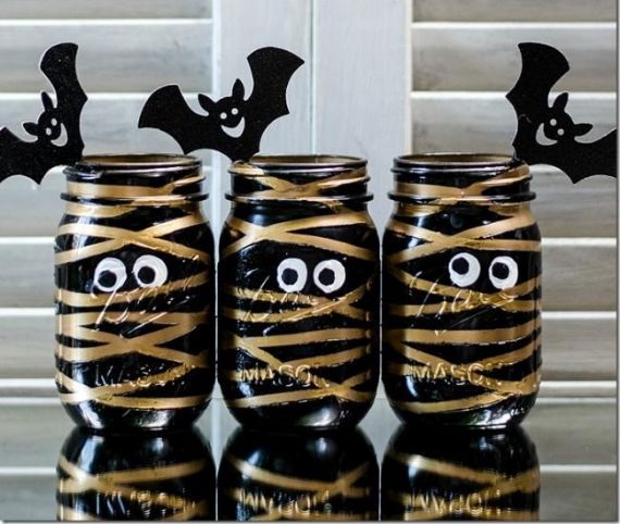 Halloween decoration featuring mason jars wrapped in gauze to resemble mummies, with googly eyes for a spooky effect.