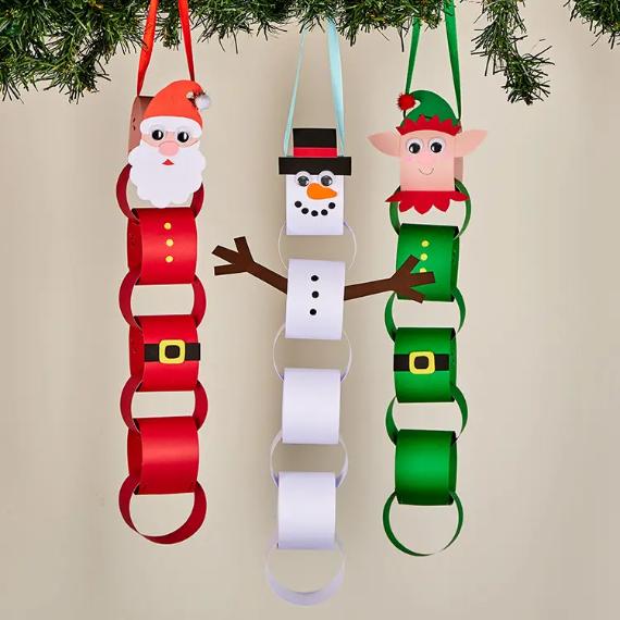 Three festive paper chains hang from a green garland. They feature Santa in red, a snowman in white, and a cheerful elf in green.