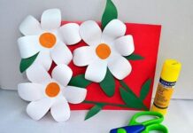 30 Paper Craft Ideas for All Occasions You’re Going to Adore A craft project with three paper daisies on a red card, accompanied by a yellow glue stick and green scissors