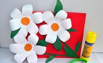 30 Paper Craft Ideas for All Occasions You’re Going to Adore A craft project with three paper daisies on a red card, accompanied by a yellow glue stick and green scissors
