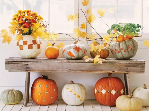 A rustic bench featuring an arrangement of pumpkins and blooming flowers, showcasing a seasonal decoration.
