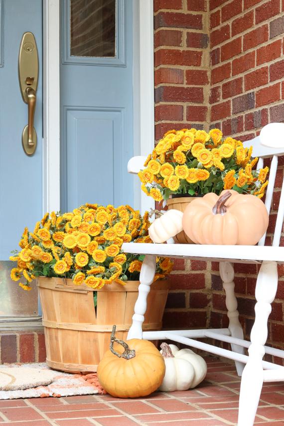 A white bench adorned with colorful pumpkins and vibrant flowers, creating a charming autumn display.