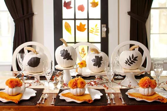  A beautifully arranged Thanksgiving table featuring white plates and decorative pumpkins.