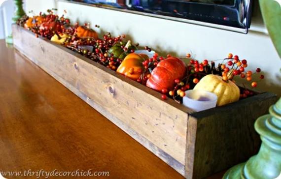 A wooden box overflowing with various pumpkins and vibrant berries, showcasing a colorful autumn harvest.
