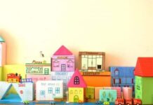 The CUTEST Cardboard Crafts for Kids Miniature cardboard cityscape with colorful buildings on a shelf.