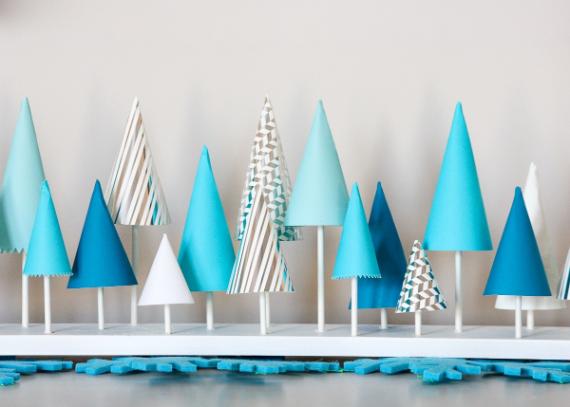 A Christmas party decorative display of paper trees in various shades of blue and white, set against a light background.