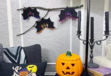 Affordable bat decorations for Halloween: DIY ideas and tips Three handmade black felt bats with colorful neon borders hanging from a natural wooden branch on a textured gray wall.