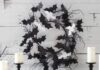 Affordable bat decorations for Halloween: DIY ideas and tips This cool black and white Halloween wreath is made of black felt bats and white ghosts plus some black twigs.