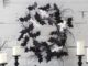 Affordable bat decorations for Halloween: DIY ideas and tips This cool black and white Halloween wreath is made of black felt bats and white ghosts plus some black twigs.
