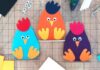 Adorable Easter Felt Craft Ideas for All Ages Three colorful felt chicken crafts—blue, orange, and purple—sit on a cutting mat with craft supplies around them, conveying a playful tone.