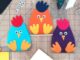 Adorable Easter Felt Craft Ideas for All Ages Three colorful felt chicken crafts—blue, orange, and purple—sit on a cutting mat with craft supplies around them, conveying a playful tone.