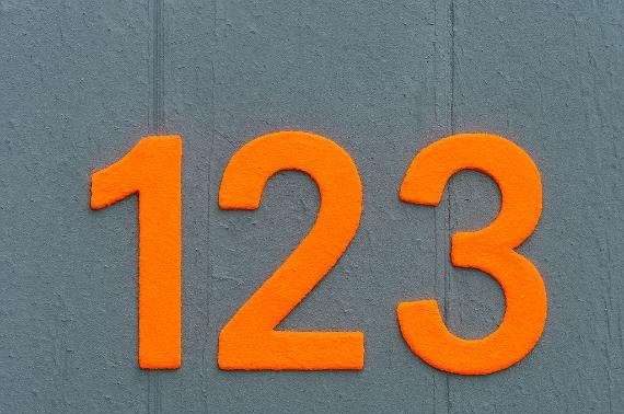 Bright orange numbers "123" are displayed on a textured gray wall. The vibrant contrast suggests clarity and simplicity in design.